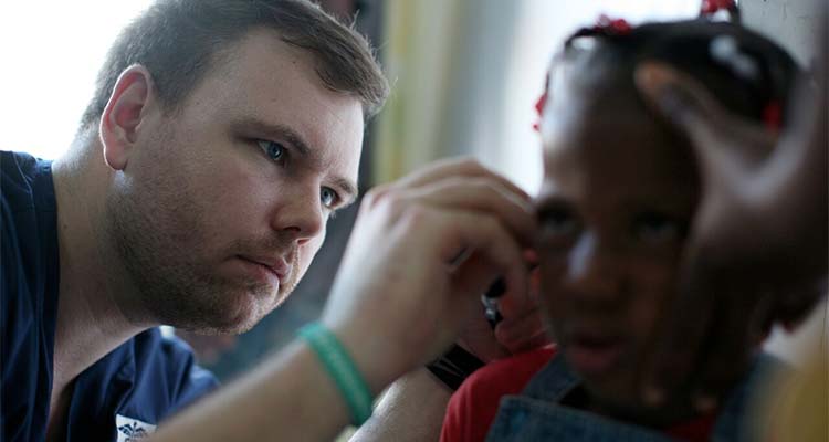 Medical professional checking local child's ear